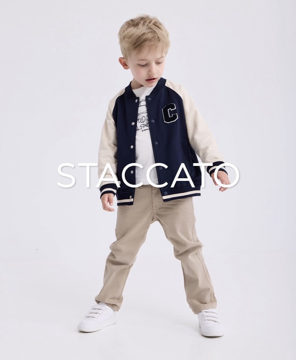 A boy wearing a navy and cream varsity jacket over a printed T-shirt